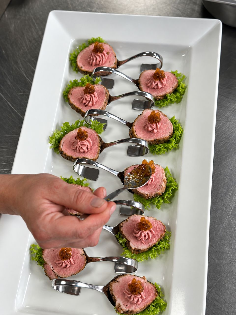 Vorspeisenlöffel mit rosa gebratenem Filet und Crème werden von Hand garniert