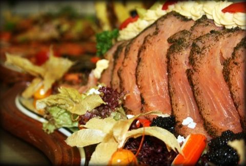 Aufgeschnittener Rinderbraten mit Garnitur auf einer Holzplatte